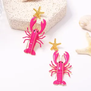 Nahaufnahme einzigartiger rosa Emaille-Hummer-Ohrringe mit goldenem Seestern-Design