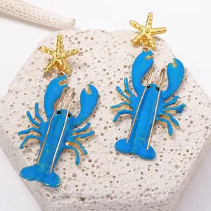 Nahaufnahme von blauen Emaille-Hummer-Ohrringen mit goldenem Seestern für den Strand
