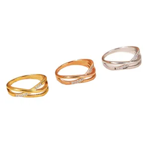Set of three minimalist titanium steel rings in gold, rose gold, and silver with small crystals.