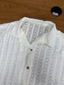 Close-up detail of a white men's short-sleeved shirt with hollow textured eyelet fabric