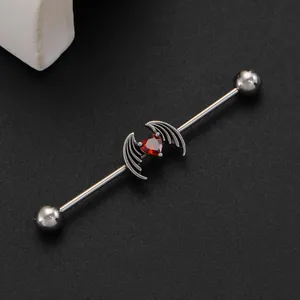 Macro view of gothic bat wing heart industrial barbell with red gemstone detail