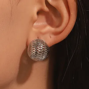 Detail view of silver hollow-out lattice sphere stud earring on ear