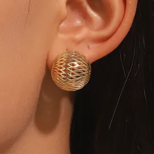 Close-up view of a minimalist gold hollow sphere earring featuring an intricate mesh design