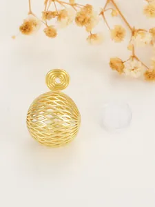 Detail view of golden hollow sphere earring with mosquito coil clip and silicone pad.