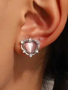 Macro detail view of a cute pink heart-shaped ear clip with sparkling zircon frame on an ear.