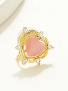 Macro detail of heart-shaped gold clip-on earring with pink stone and sparkling zircon