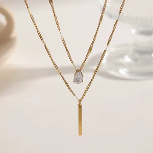 Detailed macro shot of a double-layered gold necklace with teardrop crystal and bar