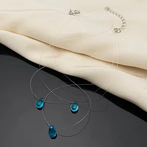 Detailed close-up view of invisible fishing line necklace with blue water-drop pendant