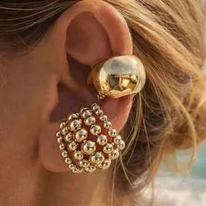 Détail d'une manchette d'oreille dorée et d'un ensemble de boucles d'oreilles perle