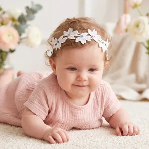 Close-up of an infant wearing a white floral lace headband with colorful rhinestones