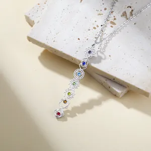 Macro detail of 7 chakra stainless steel lucky necklace with colorful stones pendant.