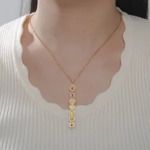 Detail view of 7 chakra yoga symbols gold necklace with colorful stones on model