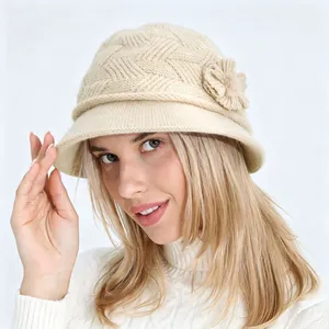 Vista detallada de un gorro de punto beige con una elegante flor lateral para mujer