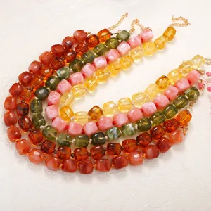 Close-up of vibrant geometric resin square bead necklaces in amber, pink and green.