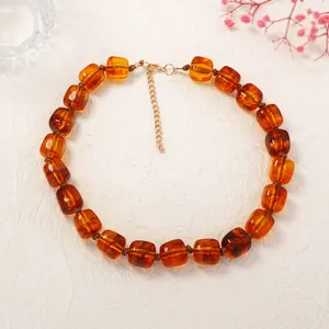 Detailed view of the amber-colored geometric resin square beads on a golden chain necklace
