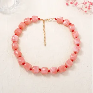 Macro detail of pink marbled resin cube beads on a stylish knotted choker necklace