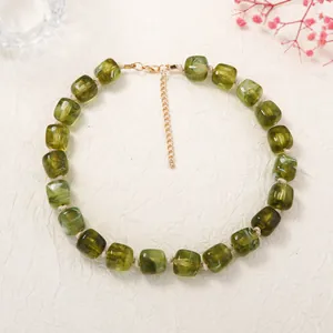 Detail view of green geometric resin square bead necklace with gold extension chain.