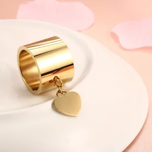 Detailansicht eines goldenen Edelstahlrings mit breitem Band und Herzanhänger-Design