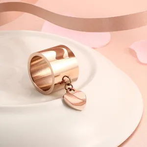 Detailaufnahme eines breiten Rings aus roségoldenem Edelstahl mit Herzanhänger