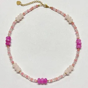 Nahaufnahme einer Perlenkette aus rosa und magentafarbenen Natursteinen mit Goldverschluss