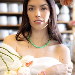 Lifestyle-Foto eines Models mit einer leuchtend grünen Natursteinkette und Rosen
