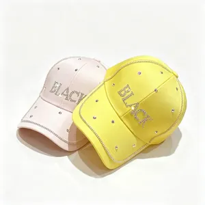 Primo piano di cappelli da baseball in raso rosa e giallo con scritta 'BLACK' in strass
