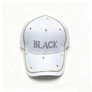 Dettaglio del cappellino bianco con scritte BLACK e finiture in strass luccicanti.