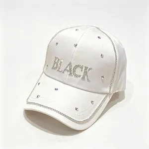 Dettaglio di cappello da baseball in raso bianco con scritta BLACK in strass e catena.