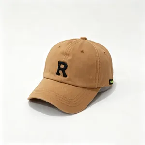 Detalle de una gorra de béisbol de color caqui con una letra R bordada en negro en 3D