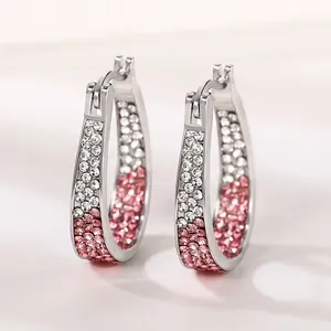 Detailed view of silver hoop earrings featuring a sparkling pink and white crystal gradient