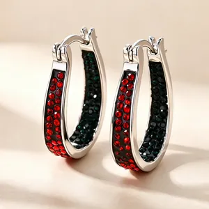 Macro detail of elegant silver U-shaped hoop earrings with red and blue rhinestones