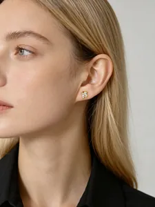 Detailed view of gold flower stud earring with clear crystals on a model's ear