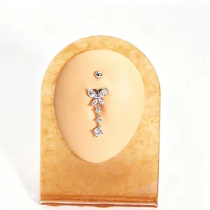 Detailed view of elegant butterfly zircon tassel navel ring on skin-toned display stand