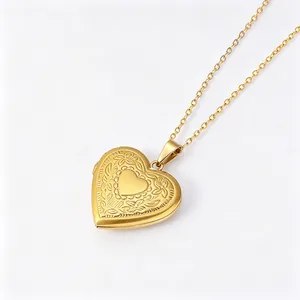 Close-up detail of a gold heart locket necklace with delicate floral engravings.