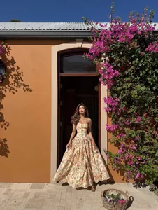 Robe longue fleurie style français avec fines bretelles dans un décor de vacances d'été