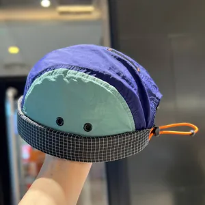 Close-up of a retro color-block 5-panel docker cap with adjustable orange toggle strap.
