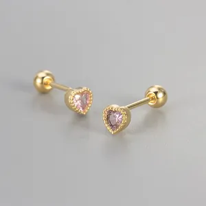 Detailed macro view of gold heart stud earrings with pink zircon and screw ball back