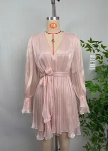 Gros plan d'une robe plissée rose brillante avec col en V élégant et lien à la taille.