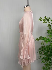 Détail de profil d'une robe rose brillante avec poignets à volants et ourlet étagé