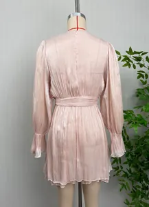 Détail d'une robe rose métallique brillante à manches longues avec ceinture à nouer