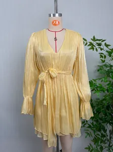 Vue détaillée du tissu plissé brillant et de la ceinture sur une robe jaune courte.