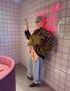 Woman wearing a striped loose-fit knit sweater in a stylish, modern bathroom setting