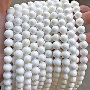 Detailed macro shot of round white natural stone beads held in hand for jewelry DIY