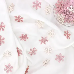 Gedetailleerd beeld van roze en witte glitter sneeuwvlok confetti op witte zijden stof