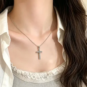 Detail view of a sparkling silver-tone cross pendant necklace worn on a neck for styling