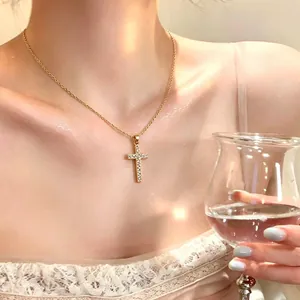 Elegant detail shot of a dainty gold-tone cross necklace featuring sparkling rhinestones