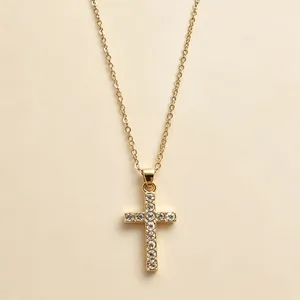 Detail shot of a gold-plated cross pendant necklace encrusted with white rhinestones.