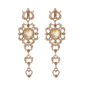 Detailed view of vintage rose gold drop earrings with champagne crystals and heart tassels.