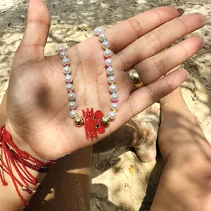 Vue détaillée d'un collier ras du cou en perles avec un joli pendentif homard rouge