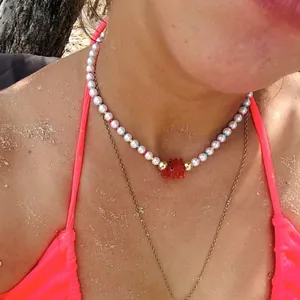 Gros plan d'un collier de perles superposé avec pendentif homard en verre rouge